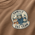 Close-up of a espresso brown t-shirt with a retro badge design showing a bear, fox, and rabbit as a “Family Ski Team.”