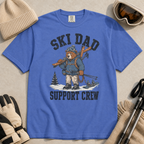 Flat lay of a mystic blue t-shirt featuring a tired bear carrying skis and ski gear, with “Ski Dad Support Crew” text.