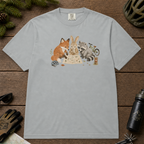 Flat lay of a granite gray t-shirt featuring a cute woodland animal trail-planning graphic with a fox, rabbit, raccoon, map, helmet, bike, and trail marker.
