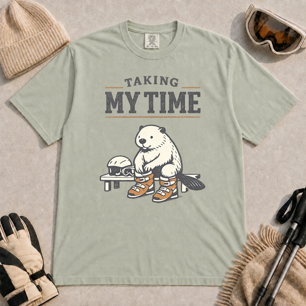 Bay tee featuring a relaxed beaver sitting on a bench in ski boots beside a helmet and goggles, with the phrase “Taking My Time.”
