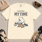 Ivory tee featuring a relaxed beaver sitting on a bench in ski boots beside a helmet and goggles, with the phrase “Taking My Time.”