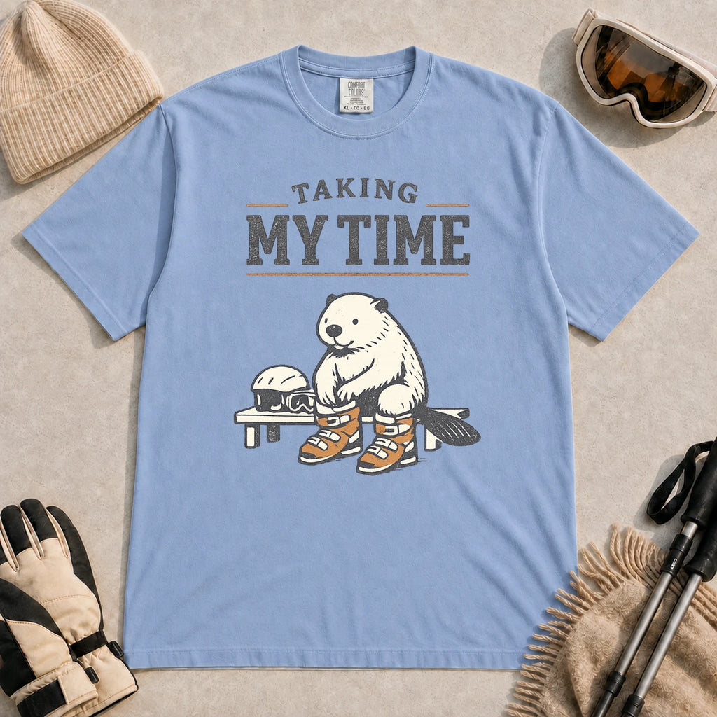 Washed Denim tee featuring a relaxed beaver sitting on a bench in ski boots beside a helmet and goggles, with the phrase “Taking My Time.”