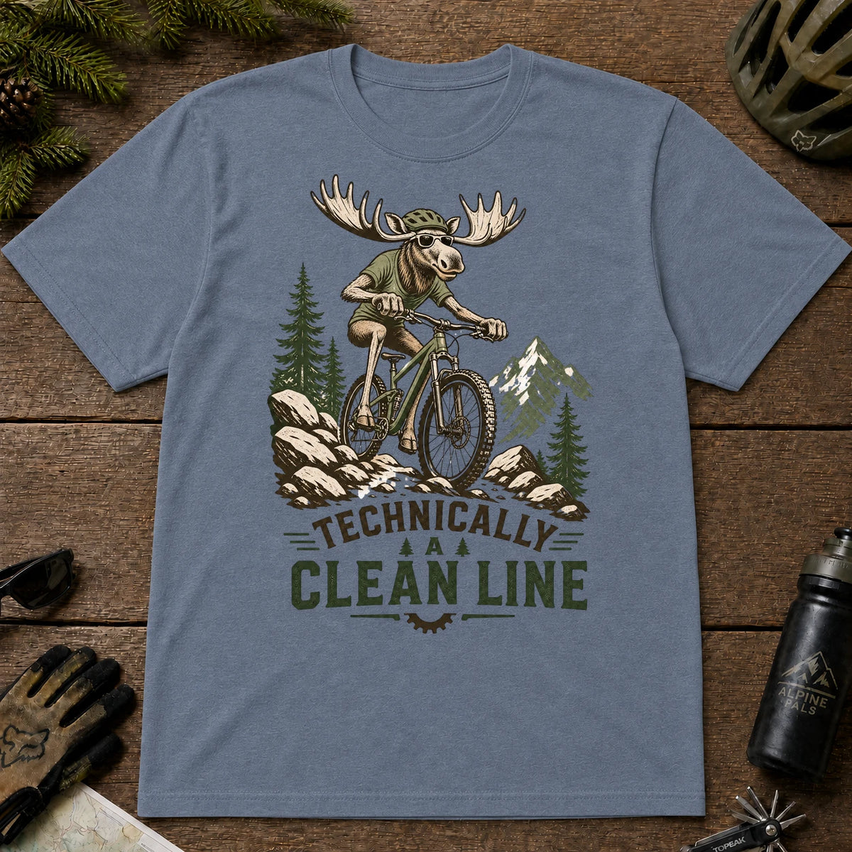 Heather Indigo tee featuring a sunglasses-wearing moose mountain biking over a rocky trail, with the phrase “Technically a Clean Line.”