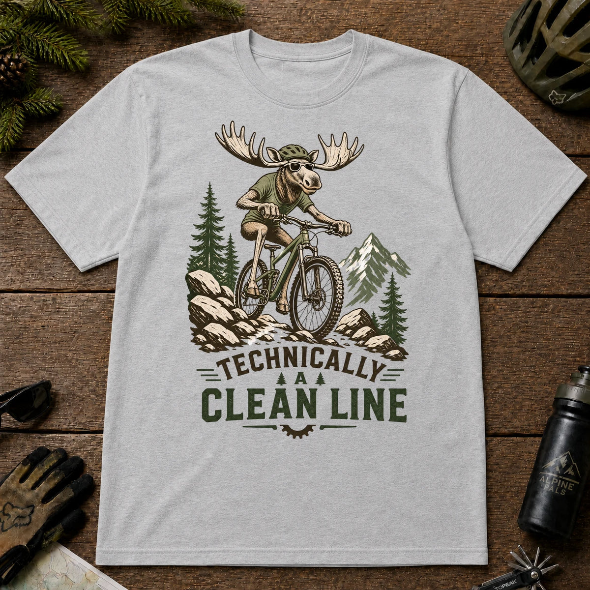 Sport Grey tee featuring a sunglasses-wearing moose mountain biking over a rocky trail, with the phrase “Technically a Clean Line.”