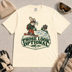 Ivory tee featuring a cautious bunny snowboarder facing a mogul run beside a “Moguls” sign above the phrase “Those Look Optional.”