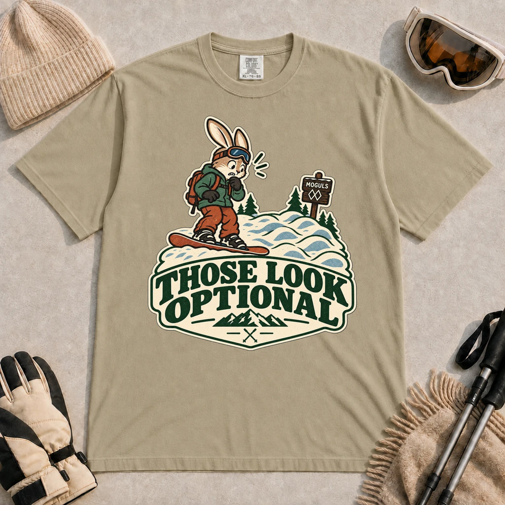 Khaki tee featuring a cautious bunny snowboarder facing a mogul run beside a “Moguls” sign above the phrase “Those Look Optional.”