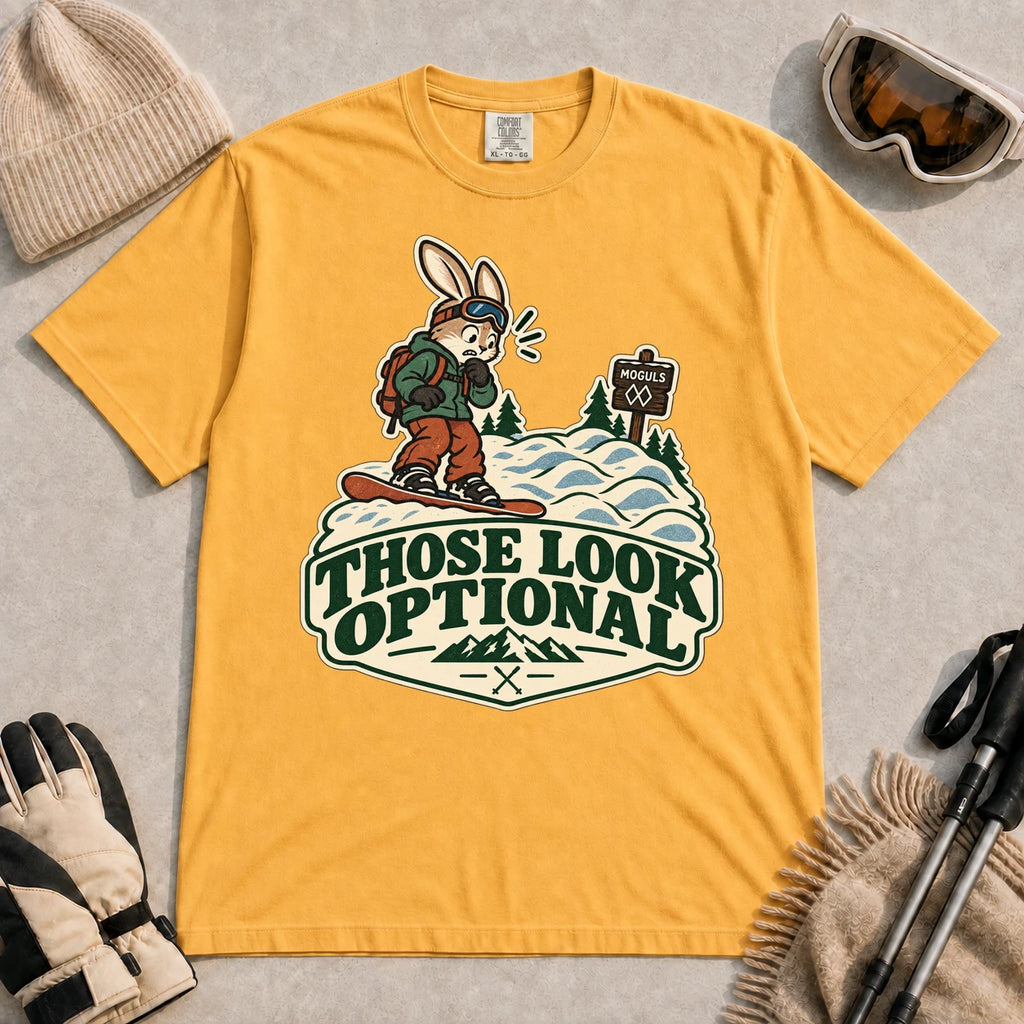 Mustard tee featuring a cautious bunny snowboarder facing a mogul run beside a “Moguls” sign above the phrase “Those Look Optional.”
