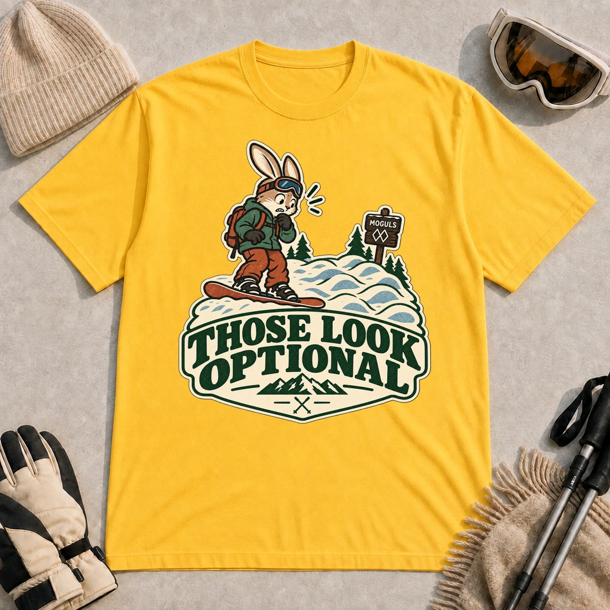 Daisy tee featuring a cautious bunny snowboarder facing a mogul run beside a “Moguls” sign above the phrase “Those Look Optional.”