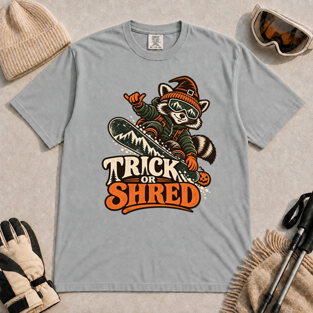 Granite tee featuring a raccoon snowboarding in Halloween gear and a witch hat above the phrase “Trick or Shred.”