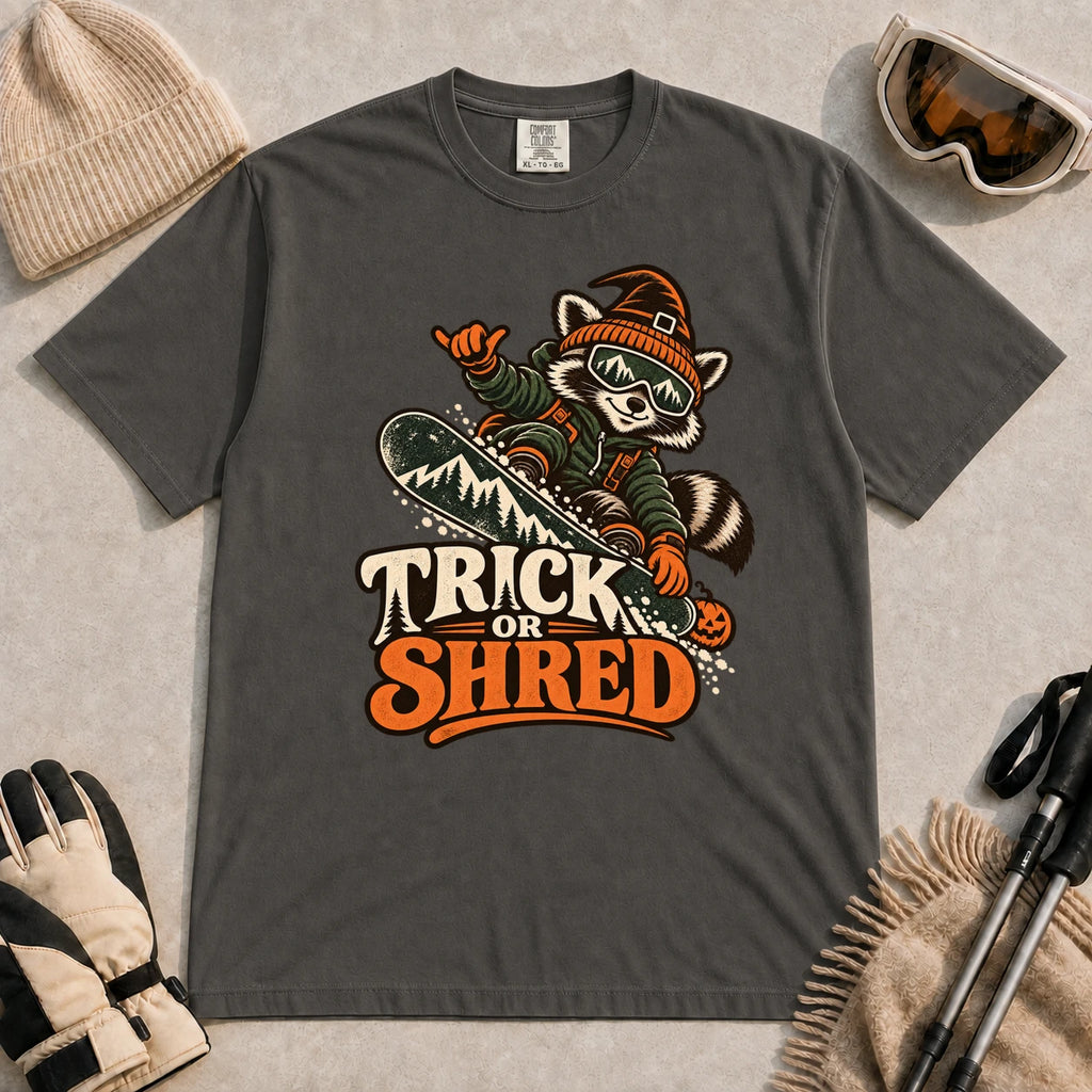 Pepper tee featuring a raccoon snowboarding in Halloween gear and a witch hat above the phrase “Trick or Shred.”