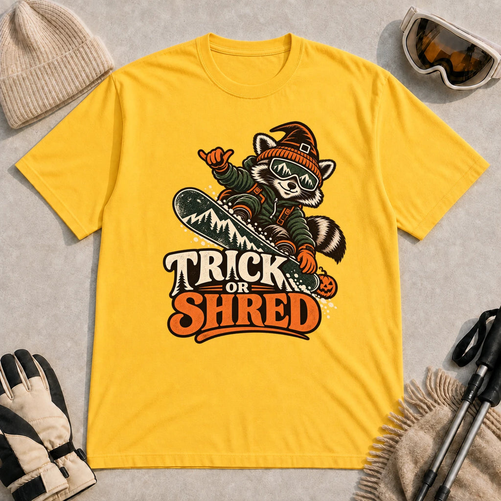 Daisy tee featuring a raccoon snowboarding in Halloween gear and a witch hat above the phrase “Trick or Shred.”
