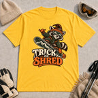 Daisy tee featuring a raccoon snowboarding in Halloween gear and a witch hat above the phrase “Trick or Shred.”