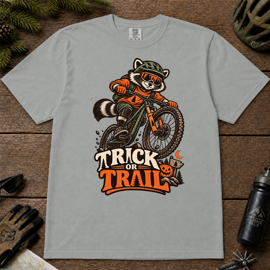 Granite tee featuring a raccoon mountain biking in Halloween gear above a pumpkin and trail sign, with the phrase “Trick or Trail.”