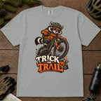 Granite tee featuring a raccoon mountain biking in Halloween gear above a pumpkin and trail sign, with the phrase “Trick or Trail.”