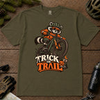 Hemp tee featuring a raccoon mountain biking in Halloween gear above a pumpkin and trail sign, with the phrase “Trick or Trail.”