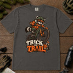 Pepper tee featuring a raccoon mountain biking in Halloween gear above a pumpkin and trail sign, with the phrase “Trick or Trail.”