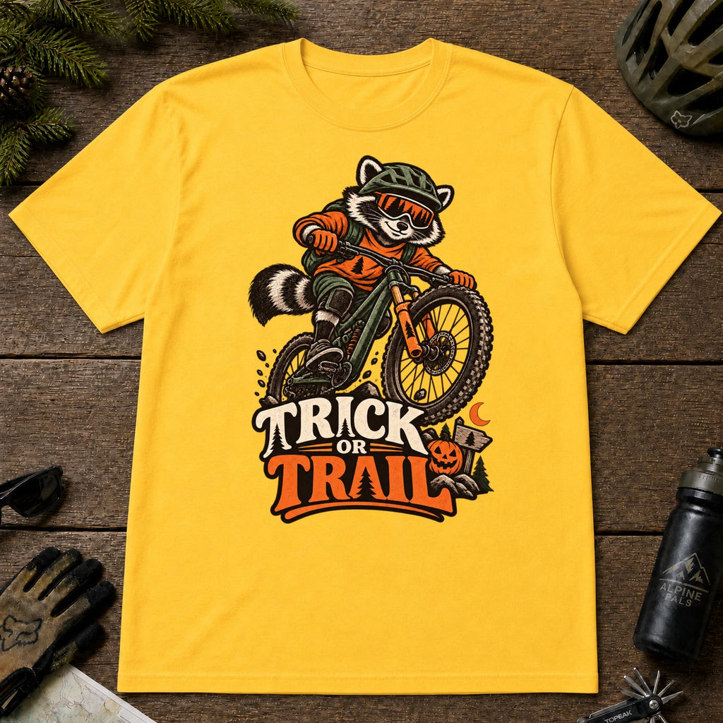 Daisy tee featuring a raccoon mountain biking in Halloween gear above a pumpkin and trail sign, with the phrase “Trick or Trail.”