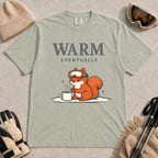 Bay tee featuring a chilly squirrel in ski goggles warming its paws beside a steaming mug in the snow, with the phrase “Warm Eventually.”