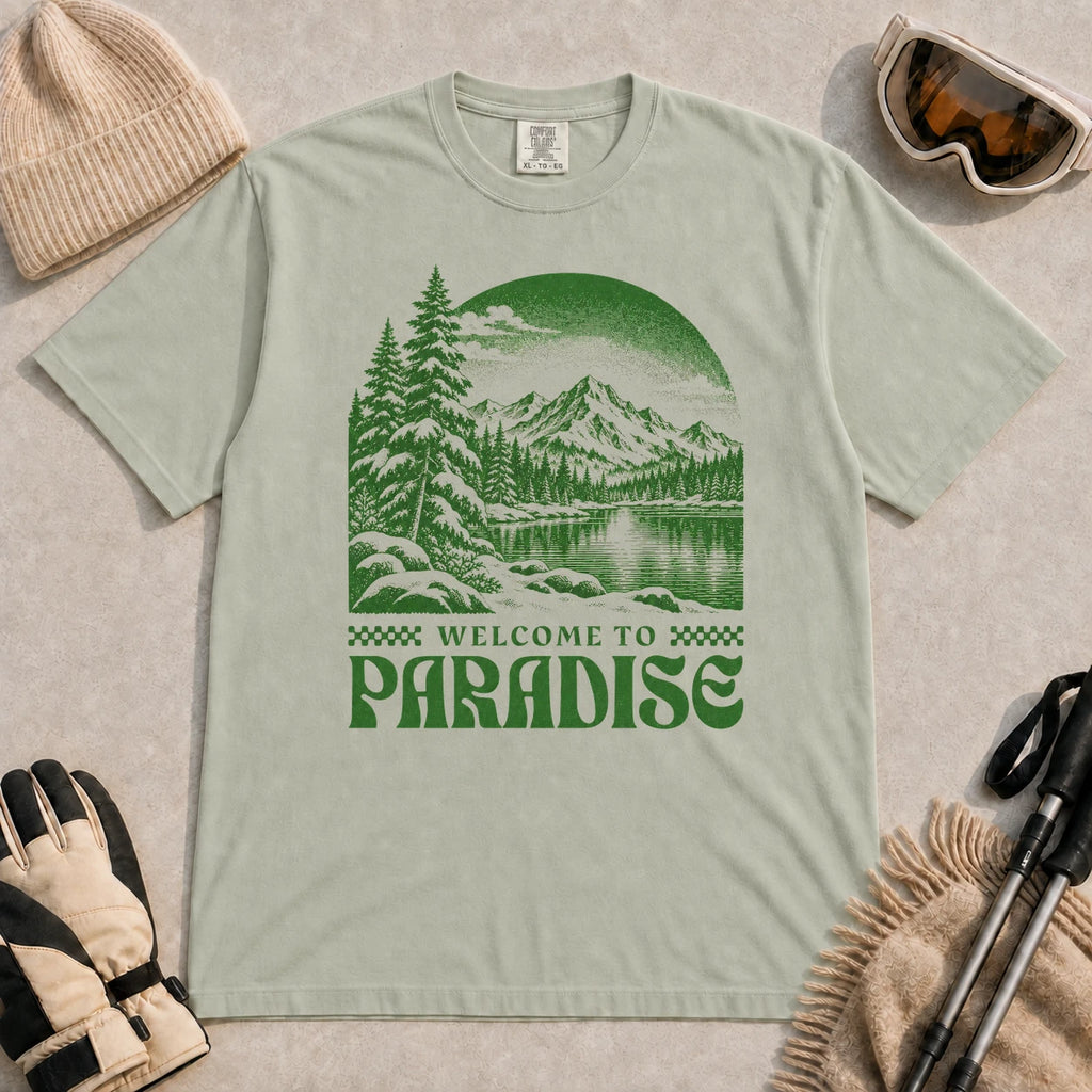 Bay tee featuring a green vintage mountain lake and evergreen forest scene with the phrase “Welcome to Paradise.”