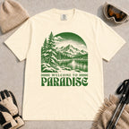 Ivory tee featuring a green vintage mountain lake and evergreen forest scene with the phrase “Welcome to Paradise.”