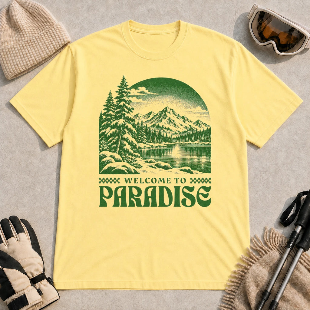 Cornsilk tee featuring a green vintage mountain lake and evergreen forest scene with the phrase “Welcome to Paradise.”