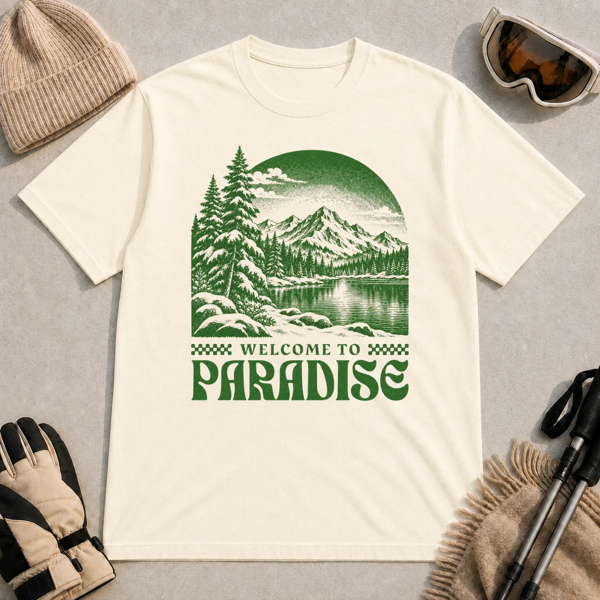 Natural tee featuring a green vintage mountain lake and evergreen forest scene with the phrase “Welcome to Paradise.”