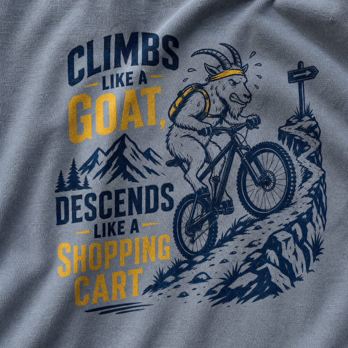 T-shirt with graphic of a goat riding a bike and text 'Climbs like a goat, descends like a shopping cart' on a gray background.