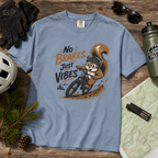 Blue t-shirt with a squirrel graphic and 'No Brakes, Just Vibes' text on a wooden surface with outdoor gear.