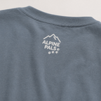 Blue jean colored shirt with 'Alpine Pals' logo on a light gray background