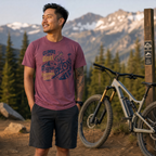 Man standing next to a mountain bike with mountains in the background