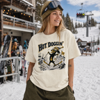 Person wearing a 'Hot Doggin' t-shirt at a snowy ski resort.