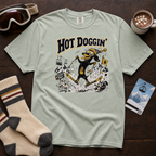 Light green t-shirt with 'Hot Doggin' graphic design on a wooden surface with accessories.