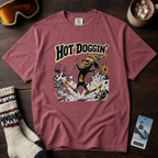 Maroon t-shirt with 'Hot Doggin' graphic design on a wooden surface with ski gear and a mug.