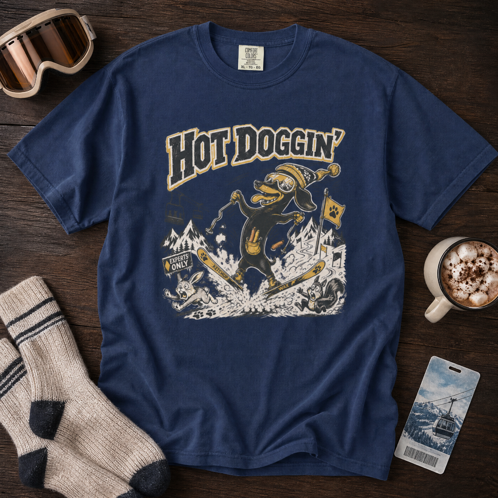 Blue t-shirt with 'Hot Doggin' graphic design on a wooden surface with accessories.