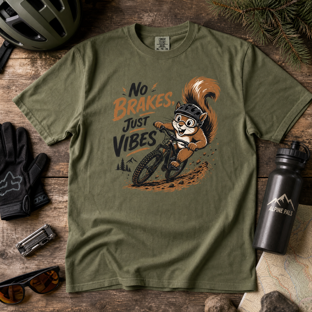 Green t-shirt with a squirrel graphic and text 'No Brakes Just Vibes' on a wooden surface with accessories.