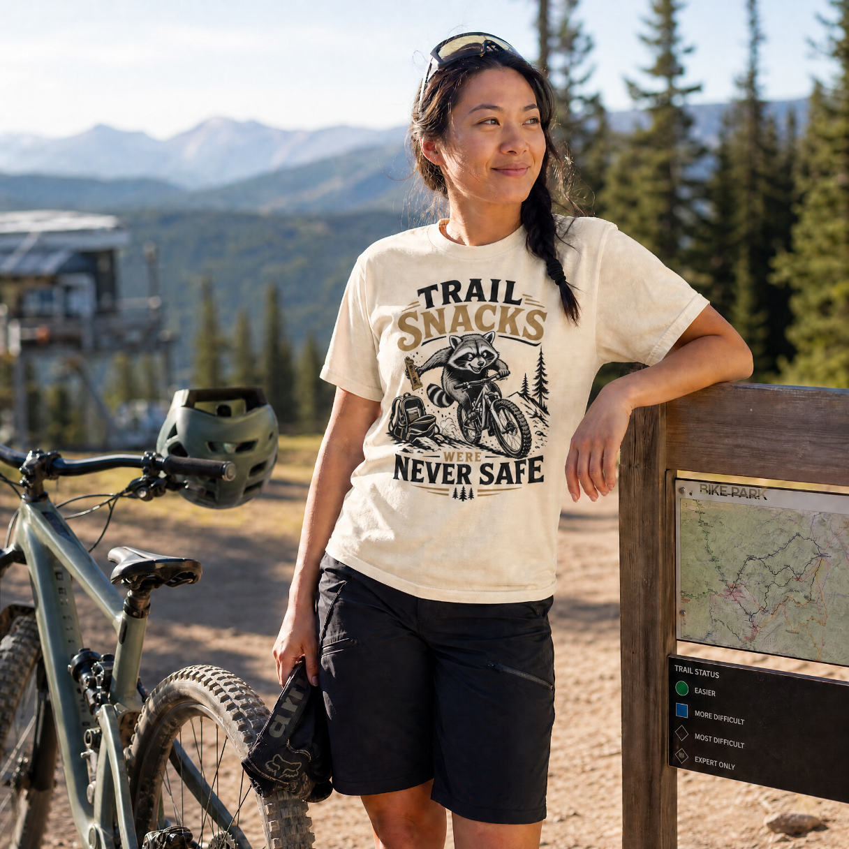 Woman in a mountain bike park wearing a t-shirt with a graphic design and text.