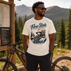 Man wearing a 'Flow State Activated' t-shirt with a mountain bike graphic, standing next to a bike in a forested area.