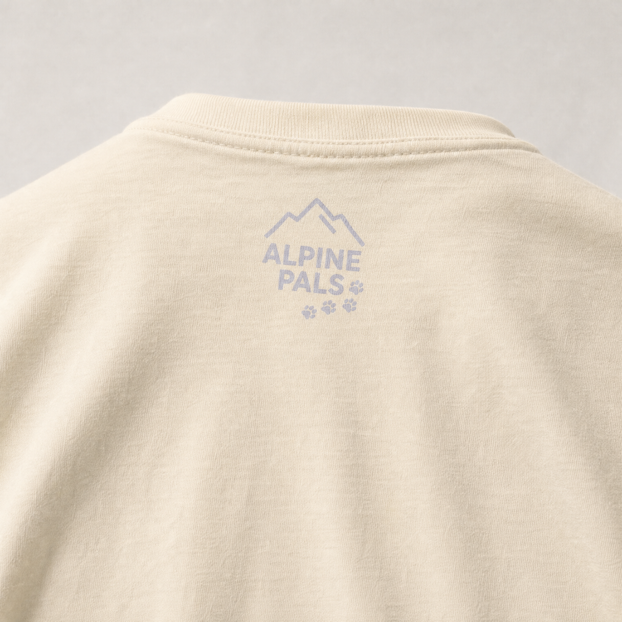 Ivory colored shirt with 'Alpine Pals' logo on a gray background