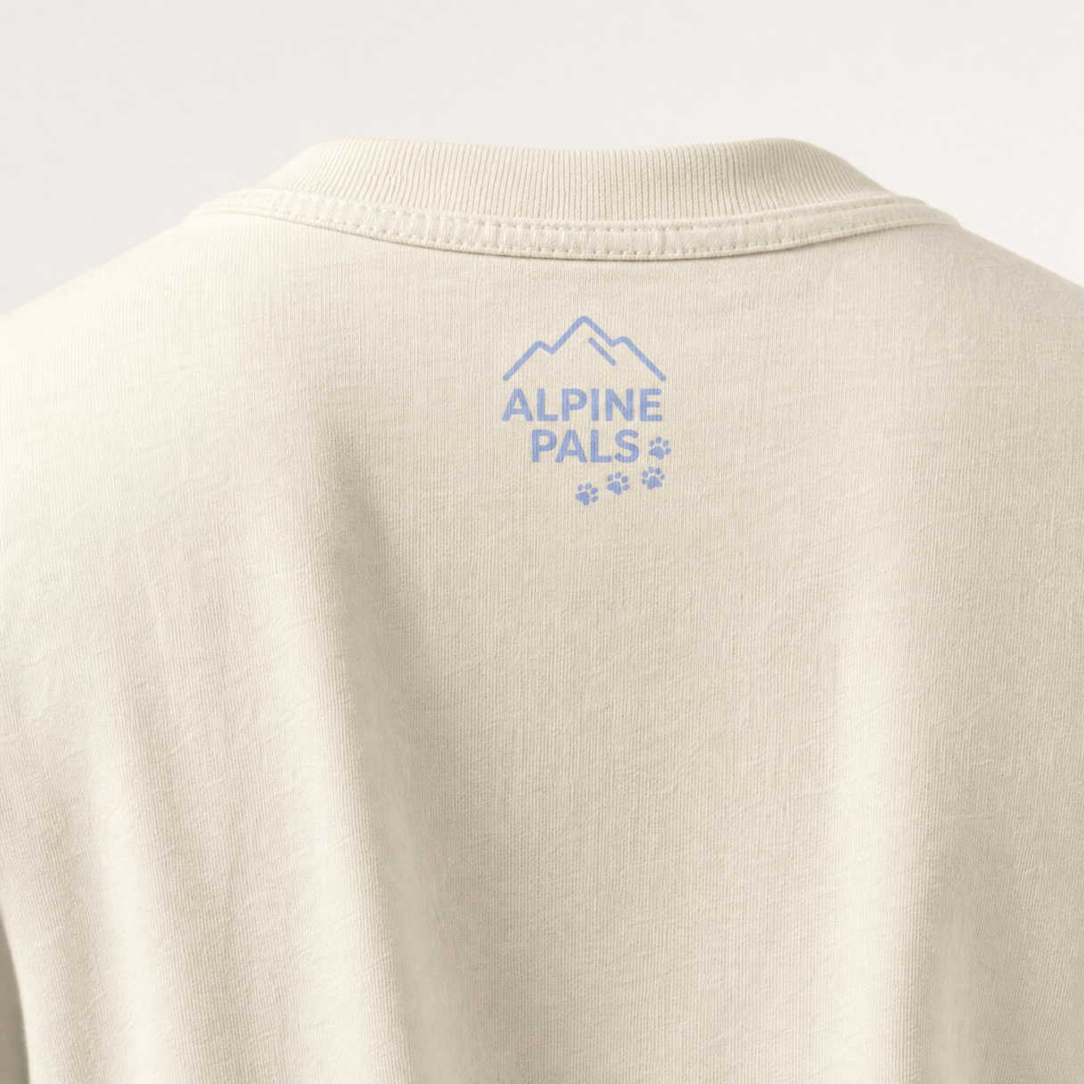 Ivory shirt with 'Alpine Pals' logo on a light gray background