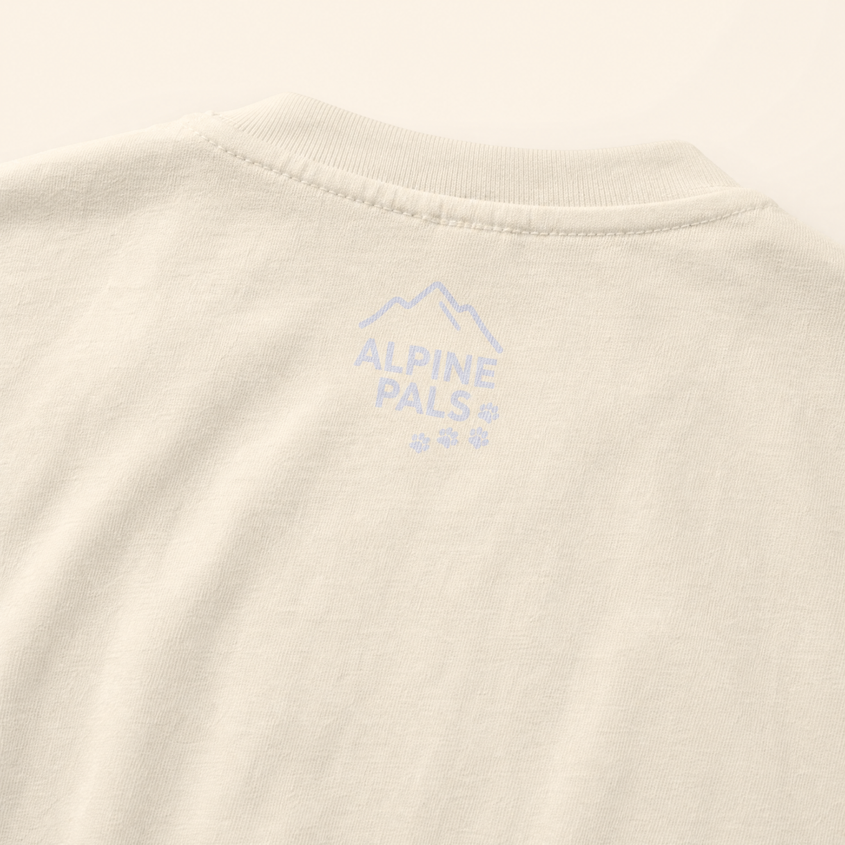 Close-up of a beige fabric with 'Alpine Pals' logo embroidered on it.