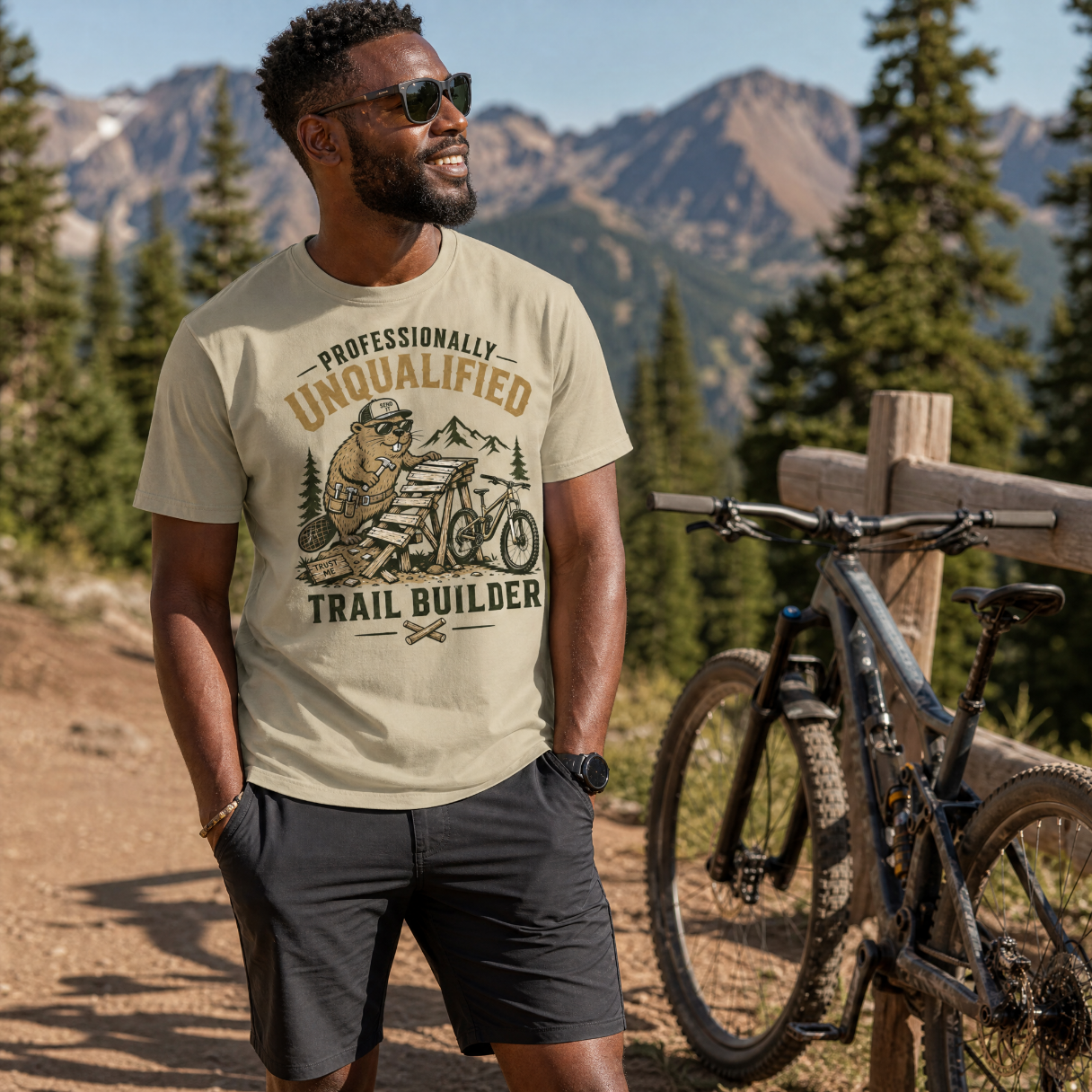 Man wearing a t-shirt with a graphic design of a trail builder in a mountainous area.
