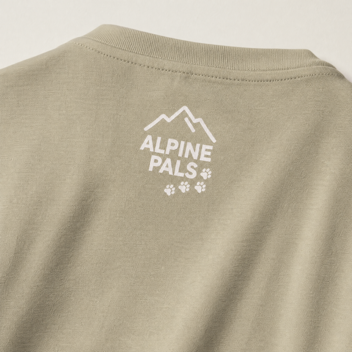 Khaki t-shirt with 'Alpine Pals' logo on a beige background