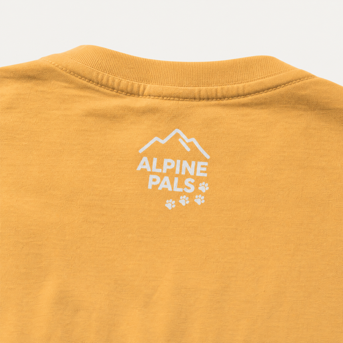 Yellow t-shirt with 'Alpine Pals' logo on a white background
