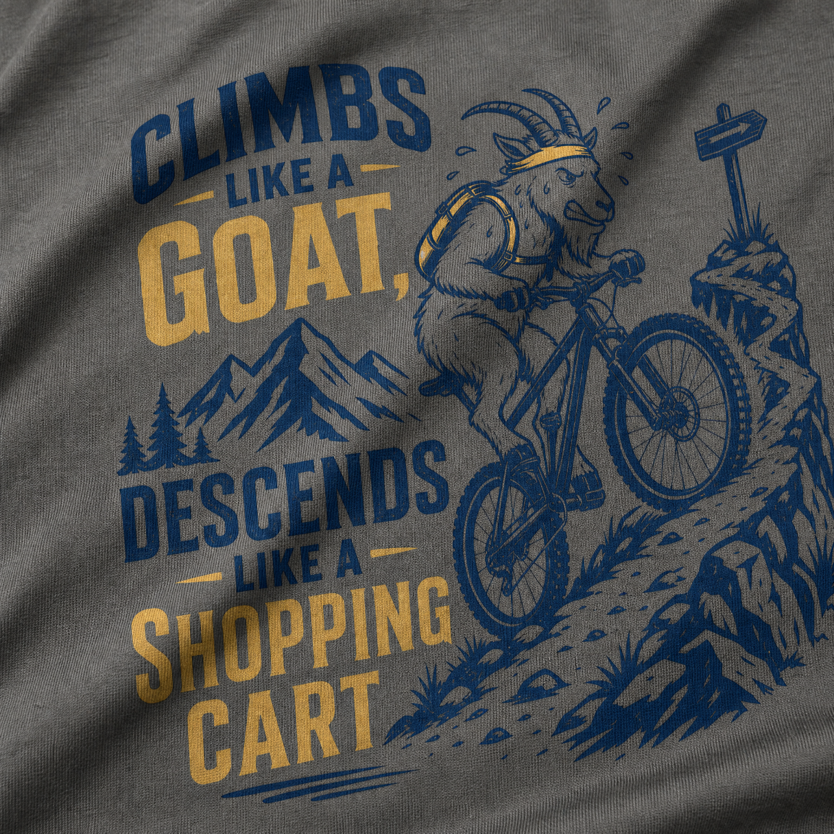 T-shirt with graphic of a goat riding a bike and text 'Climbs like a goat, descends like a shopping cart' on a gray background.