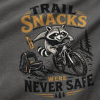 T-shirt with a raccoon riding a bike and holding a snack, text 'Trail Snacks Were Never Safe' on a gray background.