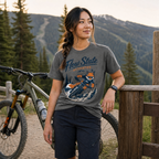 Woman wearing a 'Flow State Activated' t-shirt with a mountain bike in a scenic outdoor setting.