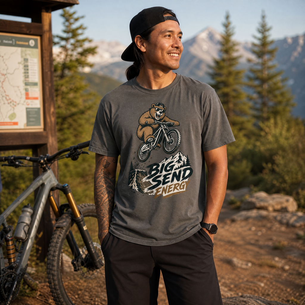 Man wearing a t-shirt with a bear graphic and 'Big Send Energy' text, standing in a mountainous area.
