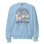 Light blue sweatshirt with a graphic of a dog by a window and 'Snowed In Loving It' text on a white background.